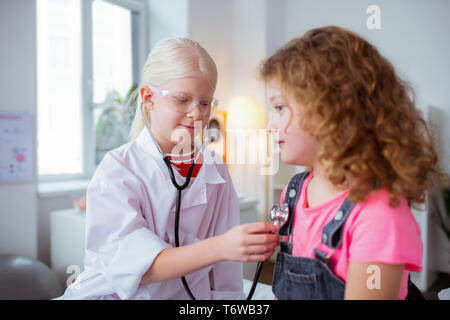 Cute ragazze riproduzione medico gioco mentre trascorrere weekend insieme Foto Stock