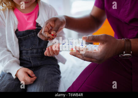 Close up di carnagione scura medico dando una pillola per bambina Foto Stock