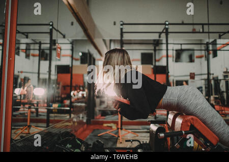 Donna attraente peso di sollevamento su Hyper Extension panca in palestra Foto Stock