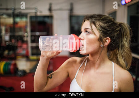 Giovani attraenti sportive acqua potabile in palestra Foto Stock