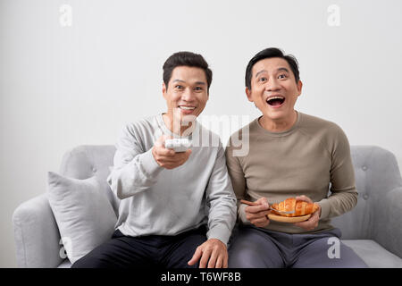 Gli uomini seduti sul divano guardando film in televisione insieme a casa. Foto Stock