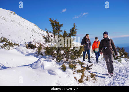 Tre persone che camminano su strade coperte di neve montagna in una giornata di sole Foto Stock