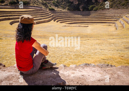 Visitatore femmina guardando le straordinarie terrazze circolari di Moray Inca sito archeologico, regione di Cusco, Perù Foto Stock