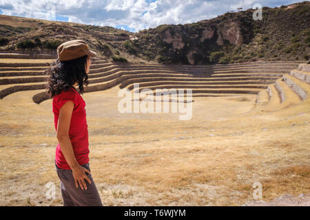 Visitatore femmina guardando le straordinarie terrazze circolari di Moray Inca sito archeologico, regione di Cusco, Perù Foto Stock