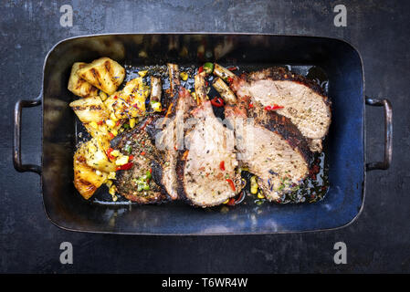 Arbusti barbecue di carne di vitello rack indietro carree arrosto con mais e ananas come vista in pianta di un piatto di supporto Foto Stock