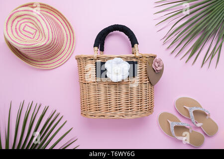 Vimini moda donna di borsa con palm di foglie e flip flop su una luce rosa pastello, sfondo vicino, viaggi e vacanze concetto, top view, mini Foto Stock