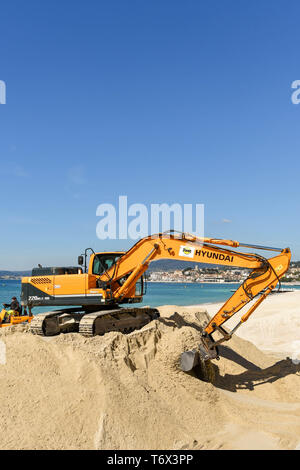 CANNES, Francia - Aprile 2019: Escavatore lavorando su una pila di sabbia viene utilizzato per migliorare la spiaggia di Cannes per la stagione delle vacanze Foto Stock