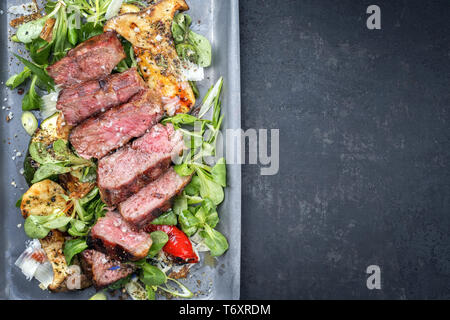 Stile moderno italiano tagliata di manzo con insalata di agnello invecchiato a secco a fette di manzo arrosto come vista dall'alto in una padella con spazio copia a destra Foto Stock