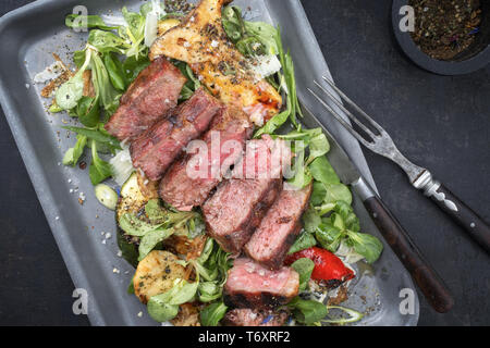 Stile moderno italiano tagliata di manzo con insalata di agnello invecchiato a secco a fette di manzo arrosto come vista dall'alto in una padella Foto Stock