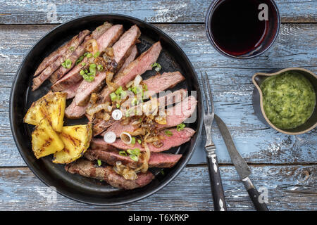 Barbecue secca wagyu invecchiato fiancheggiano bistecca con ananas e salsa chimichurri come vista dall'alto su una piastra Foto Stock