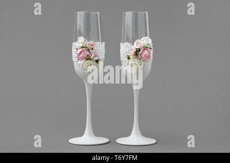 Matrimonio di due bicchieri di vino decorate con pizzo e rose su sfondo grigio. Foto Stock