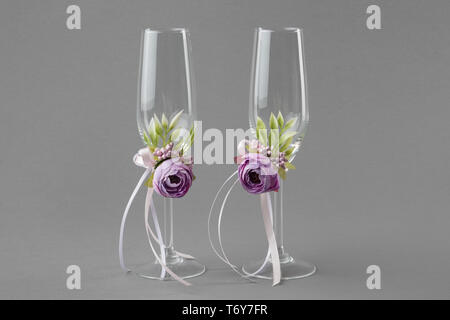 Matrimonio di due bicchieri di vino decorate con fiori viola e nastri. Foto Stock