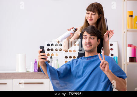 Giovane uomo attracrive visitando barbiere femmina Foto Stock