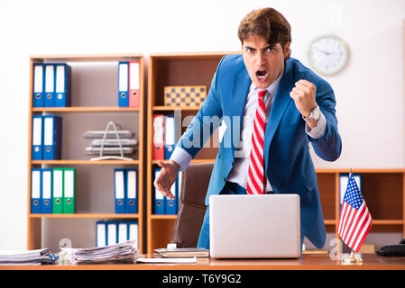 Giovane uomo politico bello seduto in ufficio Foto Stock