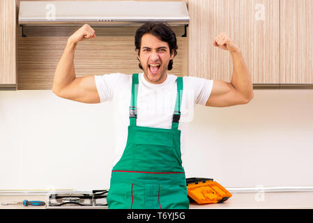 Giovane imprenditore riparazione di forno in cucina Foto Stock