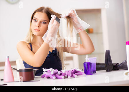 Giovane donna con arricciacapelli in Barberia Foto Stock