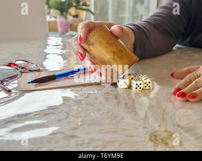 Un gioco di dadi attivo durante un gioco in close-up. un cuoio dice cup, cinque dadi bianchi, un gioco notepad, un kuli e un paio di occhiali sono sul tavolo, la Foto Stock