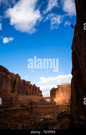 Sihlouette dell uomo rappelling off di alta scogliera nel deserto di pietra arenaria di Southern Utah. La scogliera si erge a 130 metri di altezza al fine di canyoning r Foto Stock