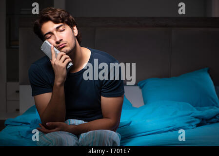 L'uomo guarda la TV di notte a letto Foto Stock