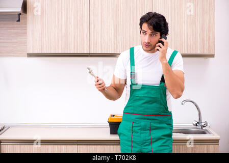 Giovani plumber riparazione toccate in cucina Foto Stock