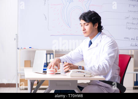 Giovane bello dentista di fronte alla lavagna Foto Stock