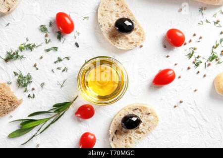 Piano di composizione dei laici con olio d'oliva, il pane e i pomodori ciliegia su sfondo chiaro Foto Stock