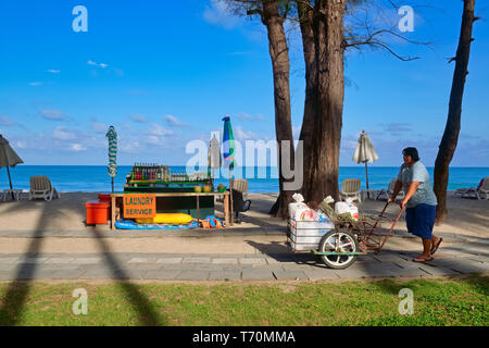 In un inizio di mattina a Bang Tao Beach, Phuket, Thailandia, un impiegato di un albergo passa un drink in stallo Foto Stock