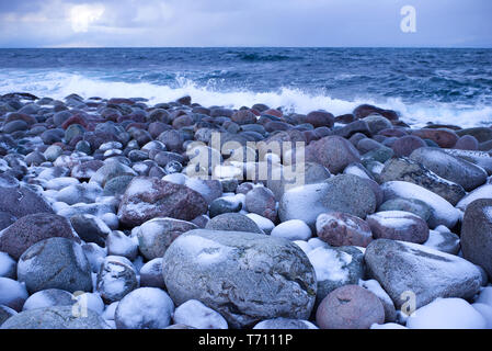 Pietre sulla costa del Mare di Barents nel febbraio del crepuscolo. Teriberka, Russia Foto Stock