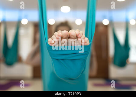 Primo piano le gambe in amaca per volare esercizi yoga. Donna facendo volare yoga esercizi di stretching in palestra. Montare e lo stile di vita di benessere. Foto Stock