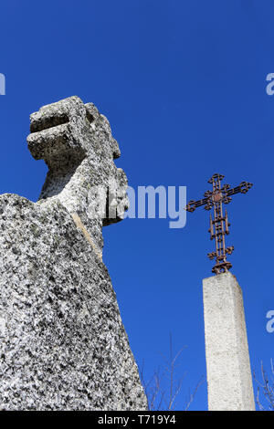 Croix en fer et en Pierre sur fond de ciel bleu. Foto Stock