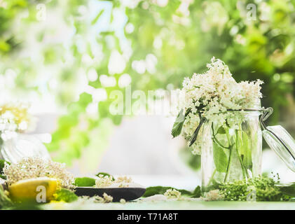 Elderflowers nel vasetto di vetro sul tavolo da cucina con limone e zucchero. In casa lâ Elderflower la cottura di preparazione. Il sambuco sciroppo di zucchero , marmellata, tè o limonata m Foto Stock