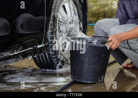 Pulire le ruote vettura con autolavaggio schiuma e serbatoio acqua nera. Foto Stock