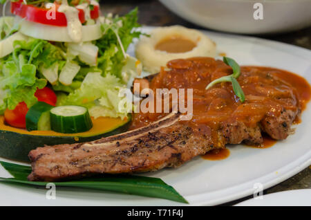 Bistecca di carne di maiale e insalata di verdure in una piastra Foto Stock