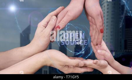 Gli uomini, le donne e i bambini con le mani in mano mostra un ologramma open source Foto Stock