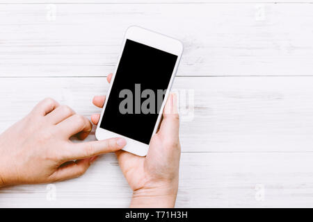 Donne mano azienda smartphone su sfondo di legno Foto Stock