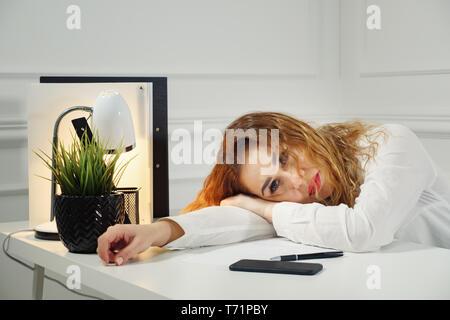 Annoiato lavoratore di sesso femminile che giacciono in corrispondenza di office desk pensare circa la soluzione del problema, immotivato imprenditrice cercare ispirazione, stanchi di lavoro monotono. La mancanza di motivazione concept Foto Stock