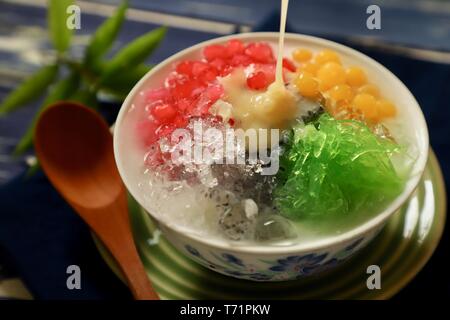 Gelido dessert asiatici di Thai rosso rubino perle, bubble jelly, agar tagliatelle, i semi del basilico e il ghiaccio tritato in latte di cocco zuppa. Foto Stock