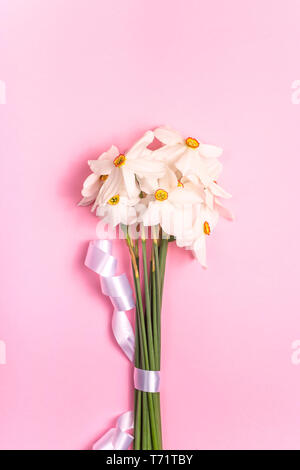 Molla delicato bouquet di daffodils bianco su uno sfondo rosa. Vista superiore, laici piatta Foto Stock