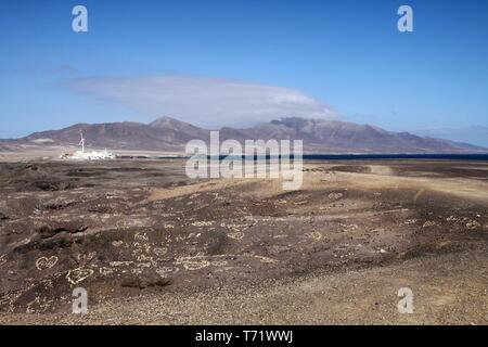 Vista sul piccolo villaggio bianco, la gamma della montagna e spot di blu oceano infinito su terreni sterili, Fuerteventura, Isole Canarie Foto Stock