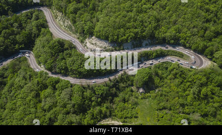 Strada tortuosa dalla high mountain pass in Russia del Sud. Grande viaggio su strada attraverso il fitto bosco. Vista aerea. Foto Stock