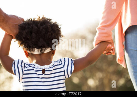 African American bambina tenendo le mani con i suoi genitori. Foto Stock