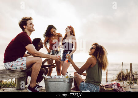 Diversi gruppi di amici appendere fuori dalla spiaggia con birre. Giovani godendo all aperto con birre. Foto Stock