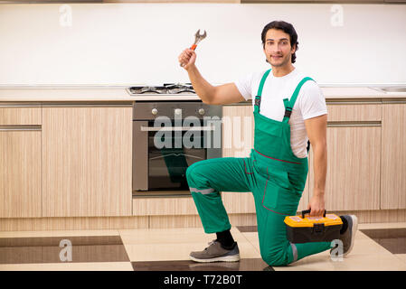 Giovane imprenditore riparazione di forno in cucina Foto Stock