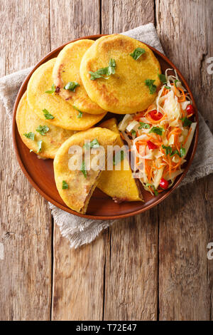 Pupusa Salvadoran servita con curtido closeup su una piastra. Verticale in alto vista da sopra Foto Stock