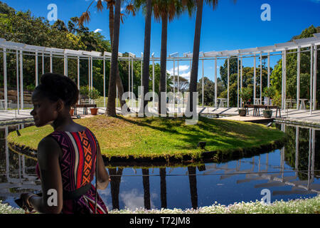 Nero donna nel calice la costruzione presso il Royal Botanic Gardens con persone rilassante nei giardini a Sydney in Australia Foto Stock