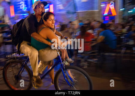 Locale giovane in sella ad una bicicletta in La Calzada una strada gastronomiche di Granada Nicaragua con un sacco di turisti e di gente del posto godendo del buon cibo all'esterno. Gr Foto Stock