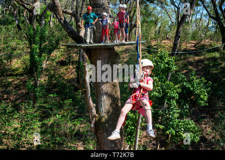 Giovane ragazza in una tettoia avventura caffetteria Las Flores Nicaragua america centrale. Zip line attraverso le cime degli alberi utilizzando i più avanzati ad alta attrezzature angolo Foto Stock