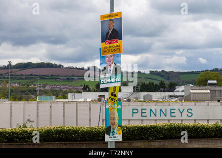 Partito politico poster affissi per un irlandese elezione con la Penneys supermercato in background Foto Stock