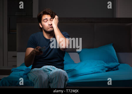 L'uomo guarda la TV di notte a letto Foto Stock