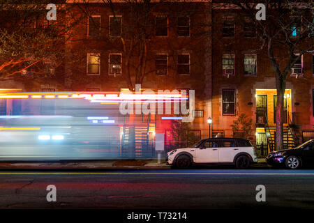 Striature di luce da una New York City firetruck o ambulanza di accelerare un vuoto di Harlem street fino a tarda notte Foto Stock